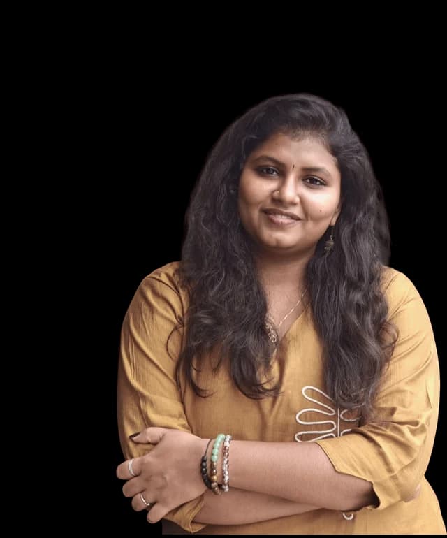 Kavya, arms folded, photographed against the Abrix red panel
